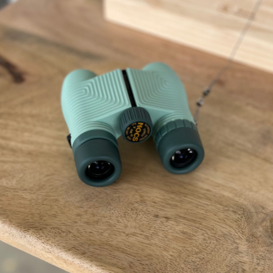 Green binoculars on a wooden surface