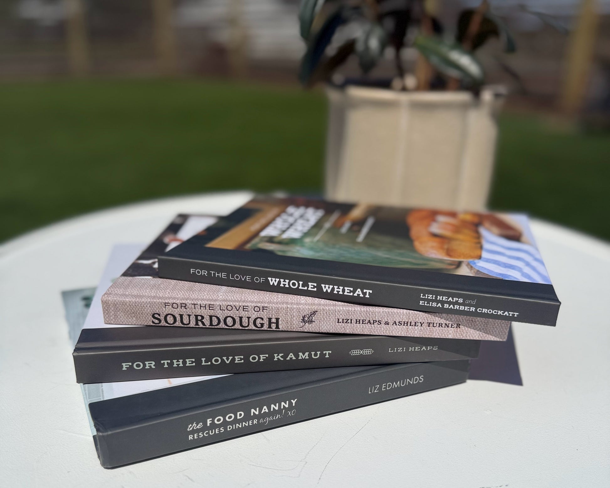 Stack of cookbooks on a table outdoors with a blurred background