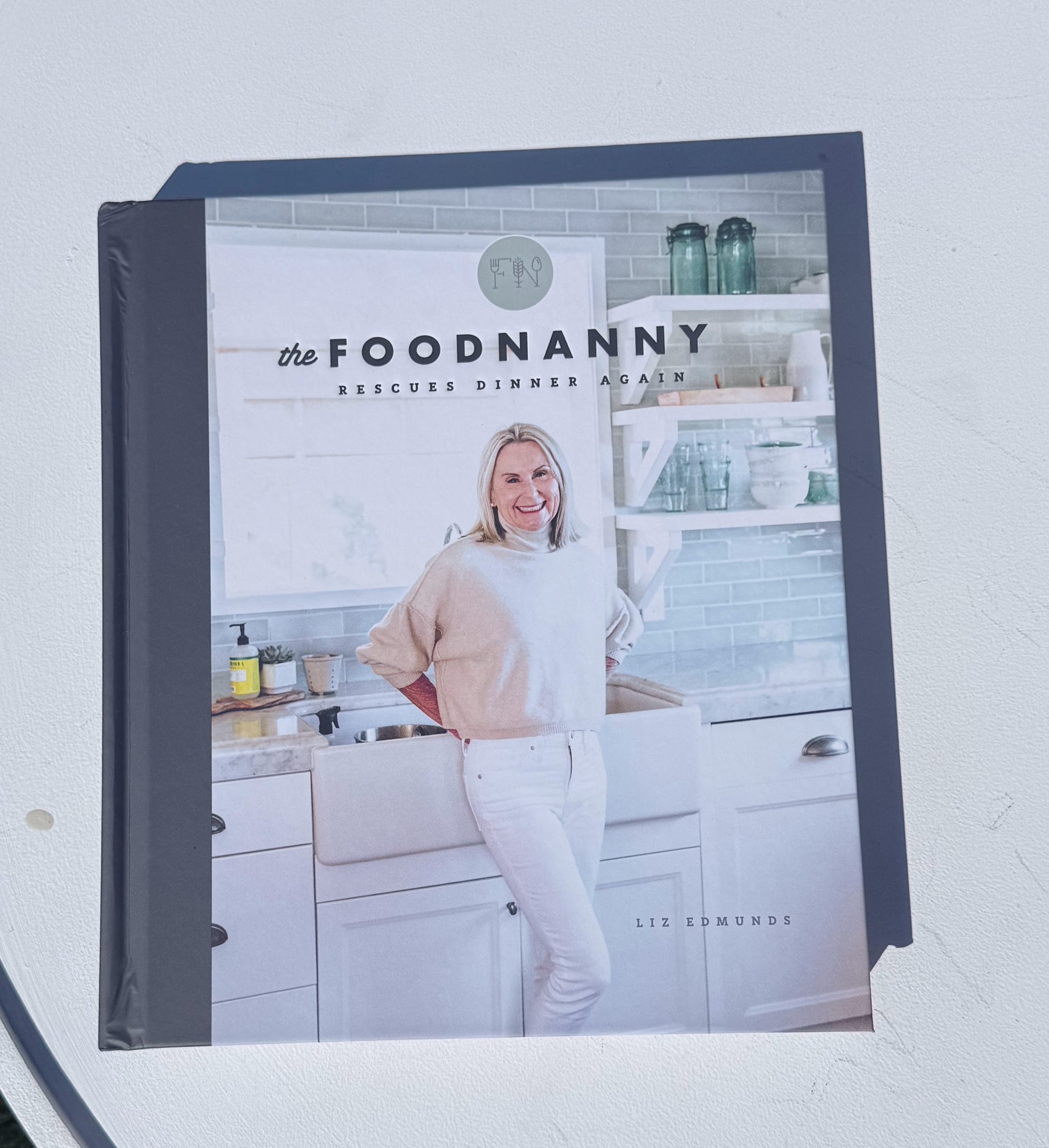 Cookbook titled 'the FOODNANNY Rescues Dinner Again' on a white surface