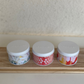Three decorative tins with floral designs on a wooden surface against a neutral wall.