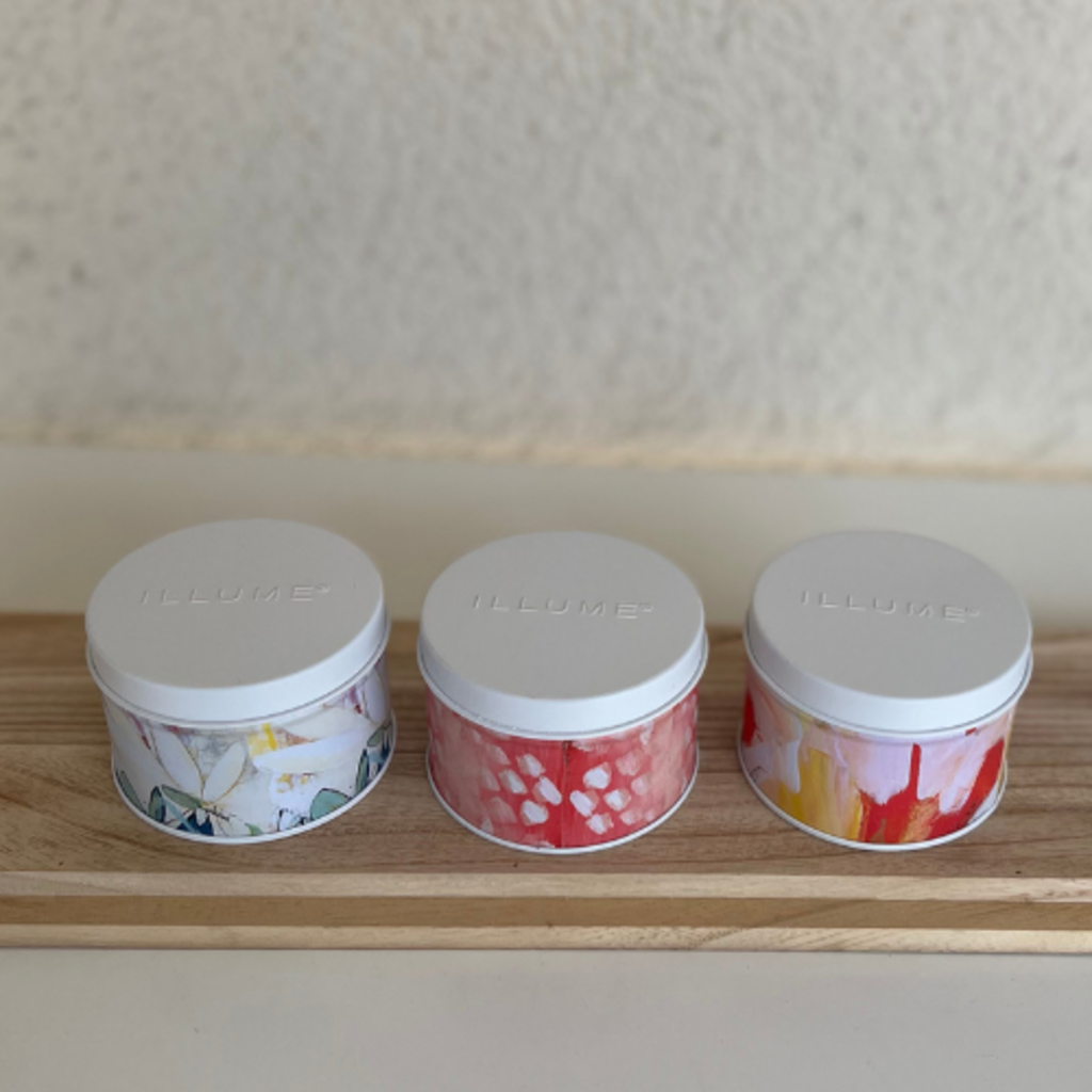 Three decorative tins with floral designs on a wooden surface against a neutral wall.