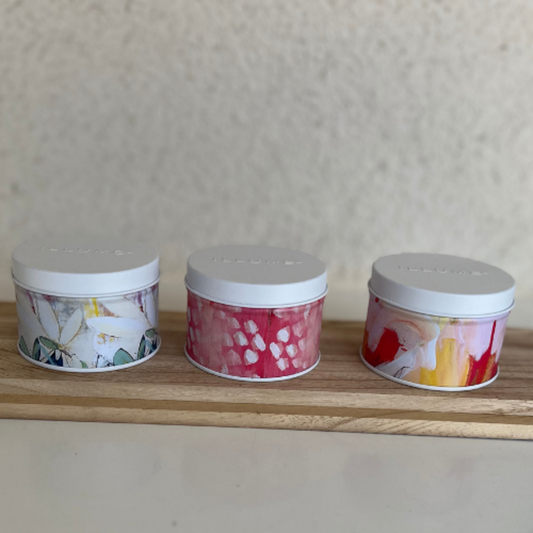 Three small containers with floral designs on a wooden surface against a neutral background